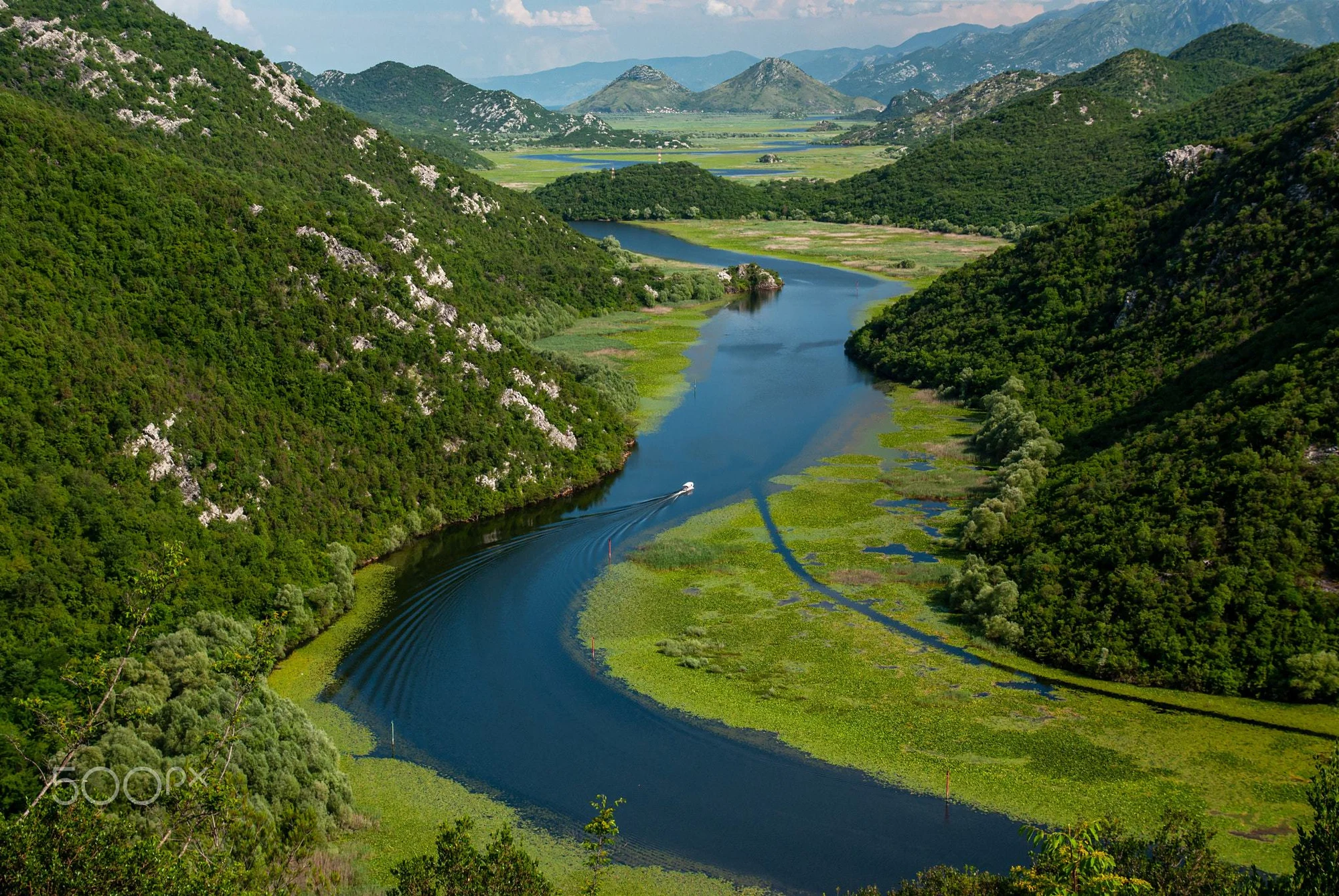 A winding river through green mountains and wetlands